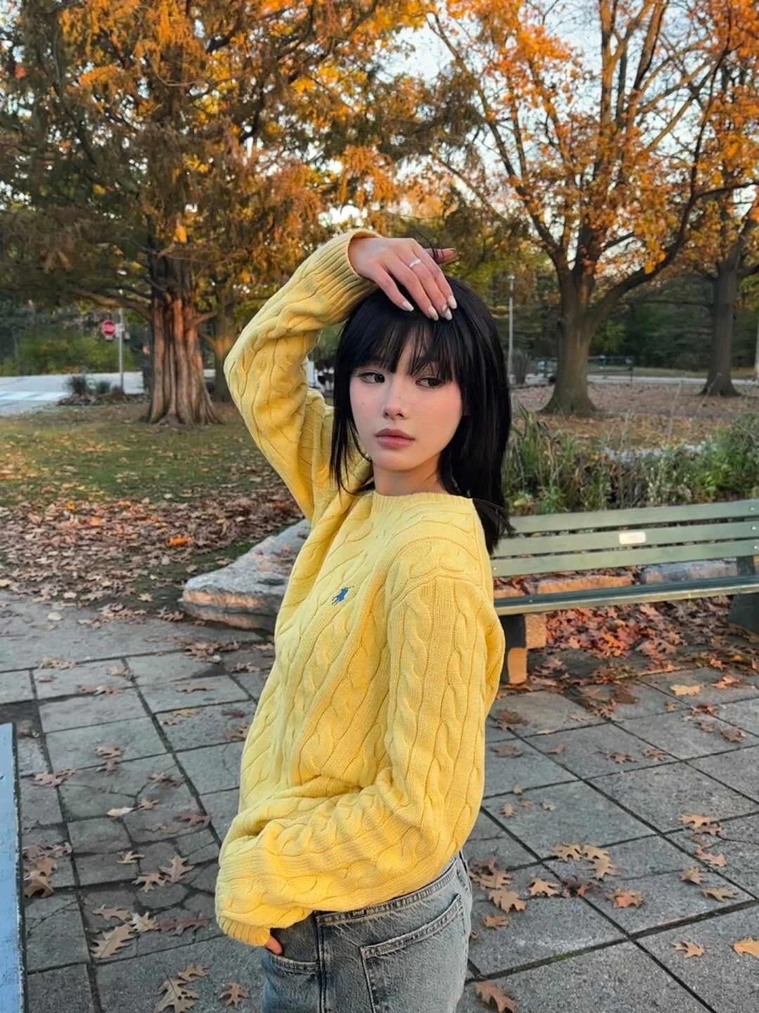 A woman wearing a bright red sweater and black pants, standing in front of a colorful wall.