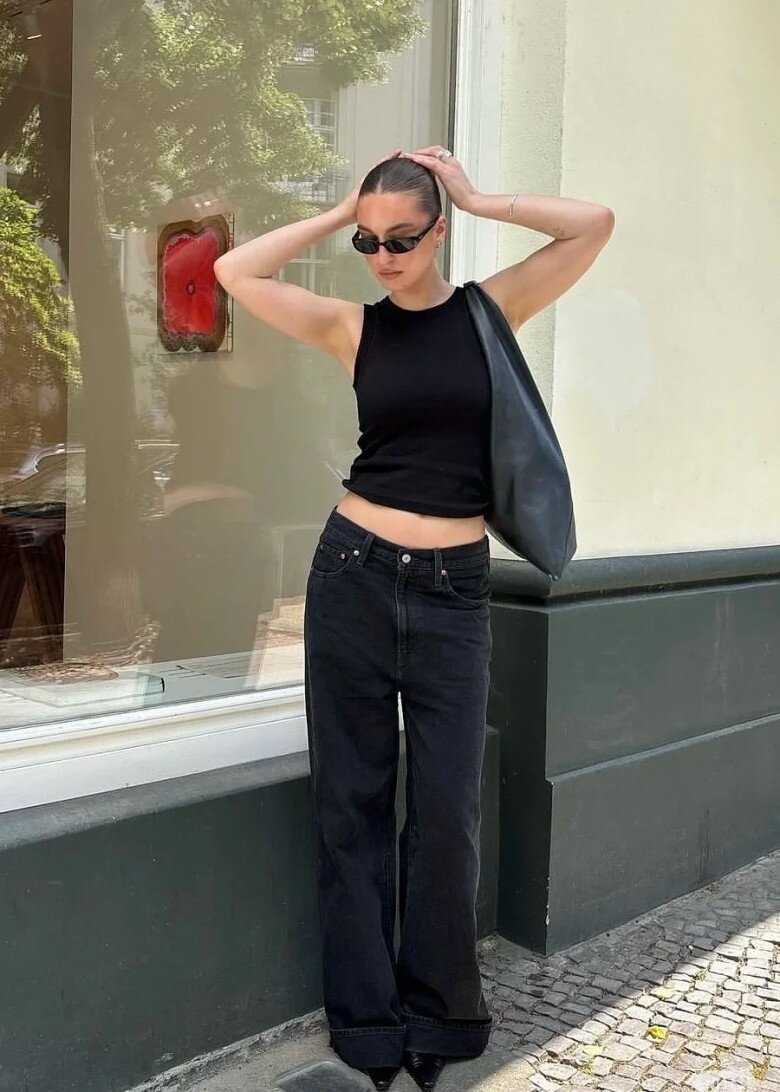 A woman wearing a cropped top and jeans