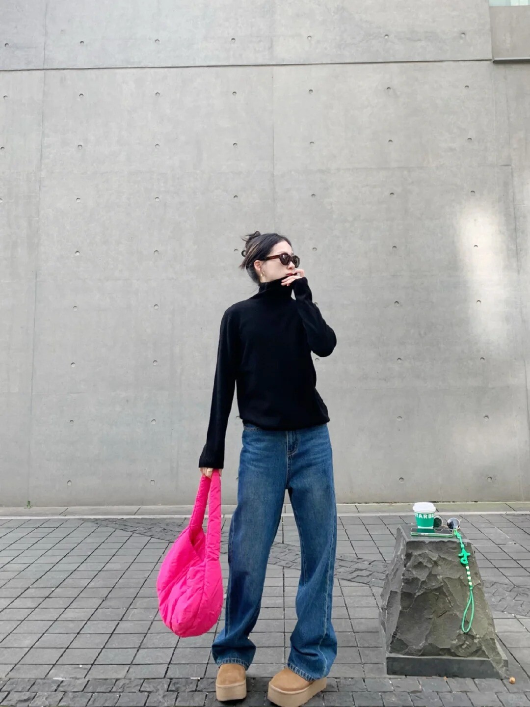 A woman wearing a white turtleneck sweater, blue jeans, and white sneakers, posing on a street.