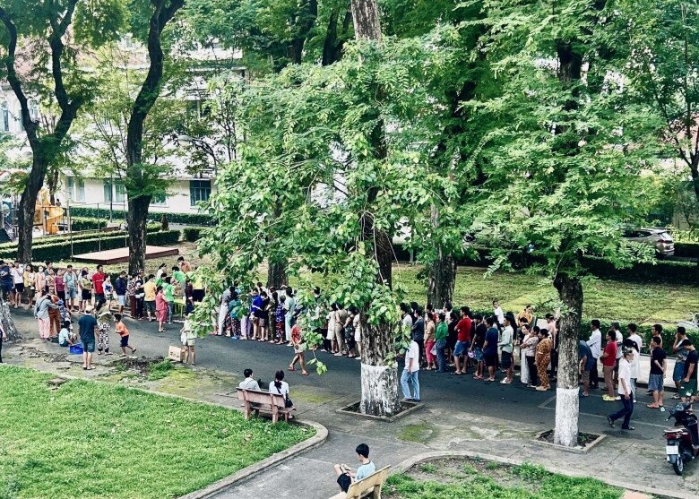 Hàng trăm phụ huynh ẵm theo con nhỏ đứng xếp hàng ngay ngắn để chờ đợi nhận cháo, sữa miễn phí tại BV Nhi đồng 2