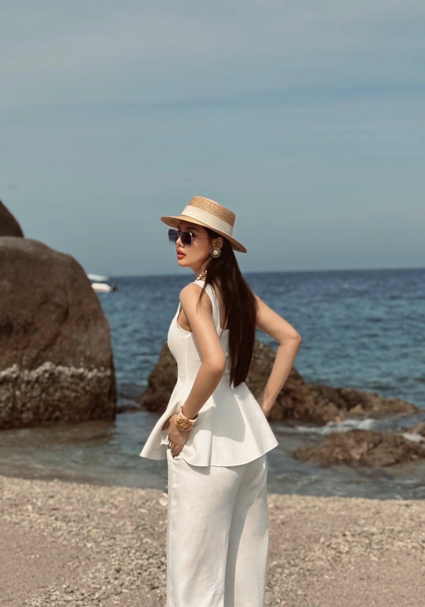 Người đẹp diện bộ trang phục trắng tinh khôi gồm áo peplum ôm sát tôn dáng phối cùng quần ống rộng, tạo nên tổng thể vừa nữ tính, vừa thời thượng. Phom dáng ôm nhẹ phần eo kết hợp chi tiết xòe nhẹ ở hông giúp cô khoe khéo đường cong mà vẫn giữ được sự nền nã, kín đáo.