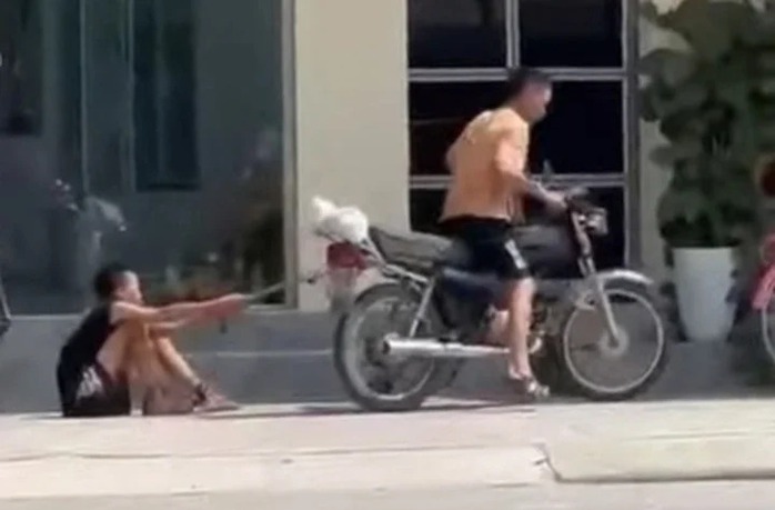 Hình ảnh bé trai bị bố xích chân kéo lê trên đường