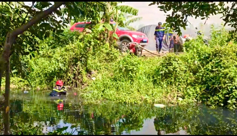 Cảnh sát ngâm mình nhiều giờ dưới kênh nước để xử lý rác, tạo thuận lợi cho việc hút nước dập lửa. Ảnh: NT
