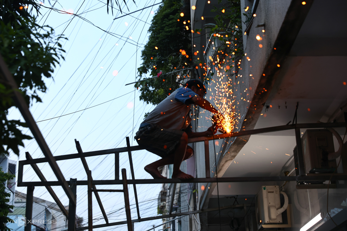 Thợ trèo lên các mái hiên cao khoảng 4 m để cắt các khung sắt thép. Theo các hộ dân, phần mái hiên tầng trệt cư xá được gia cố thêm để che nắng mưa, hạn chế nước từ các tầng trên chảy xuống.