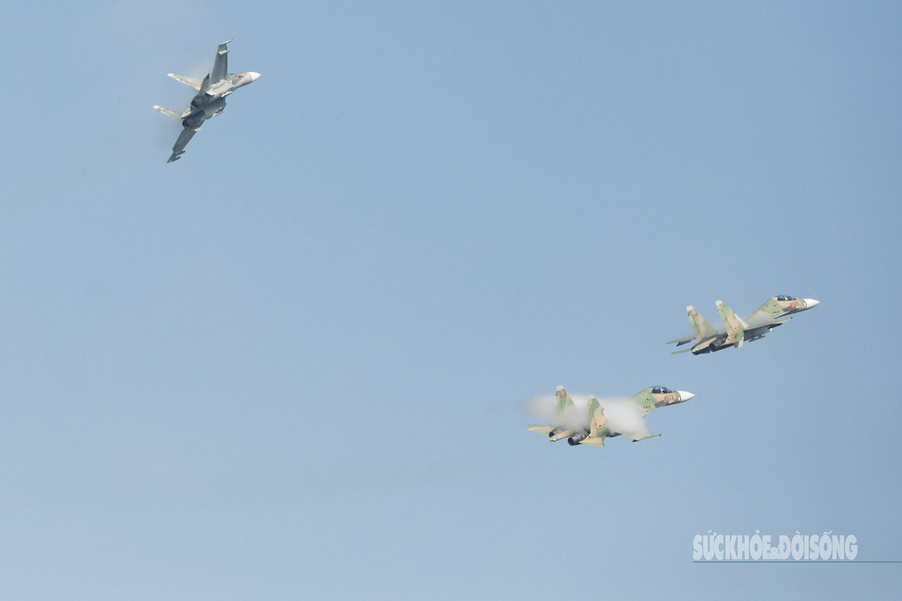 Từng cặp Su-30MK2, động cơ gầm vang, lao vút lên trời theo đội hình 2-2-1-2-1. Mỗi cú bứt tốc, luồng khí động mạnh khiến không khí quanh cánh ngưng tụ thành làn khói trắng bao phủ.