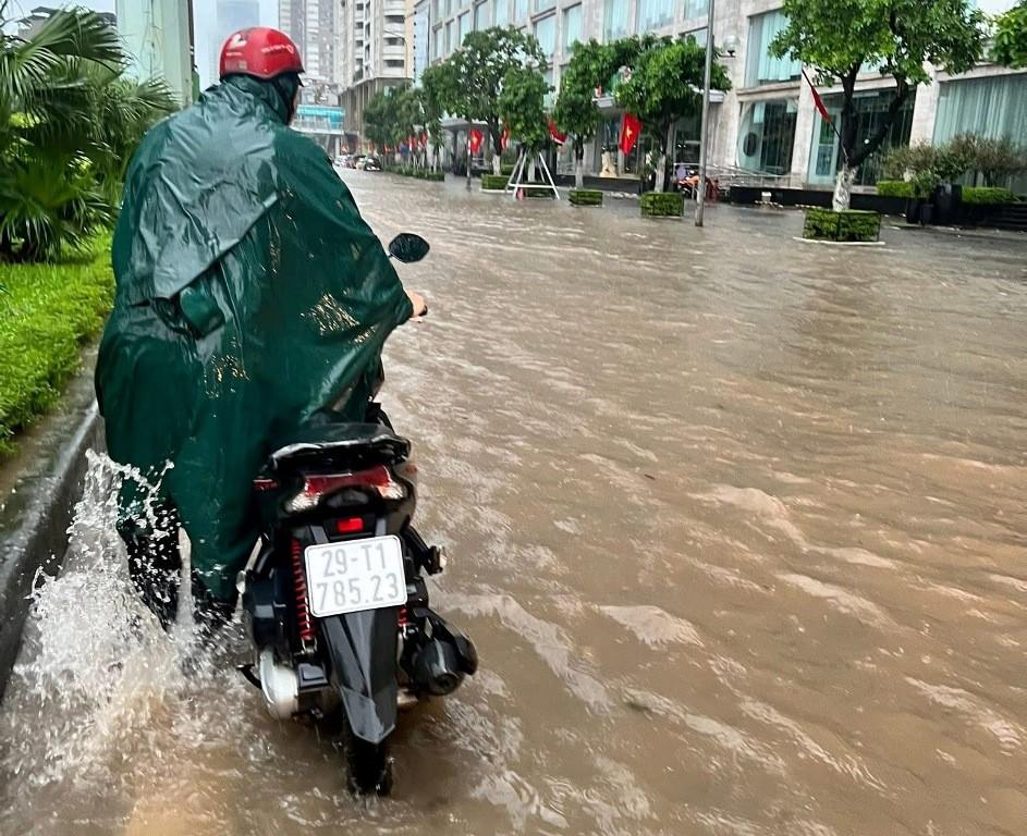 Người dân phải dắt xe máy do bị nước ngập chết máy.