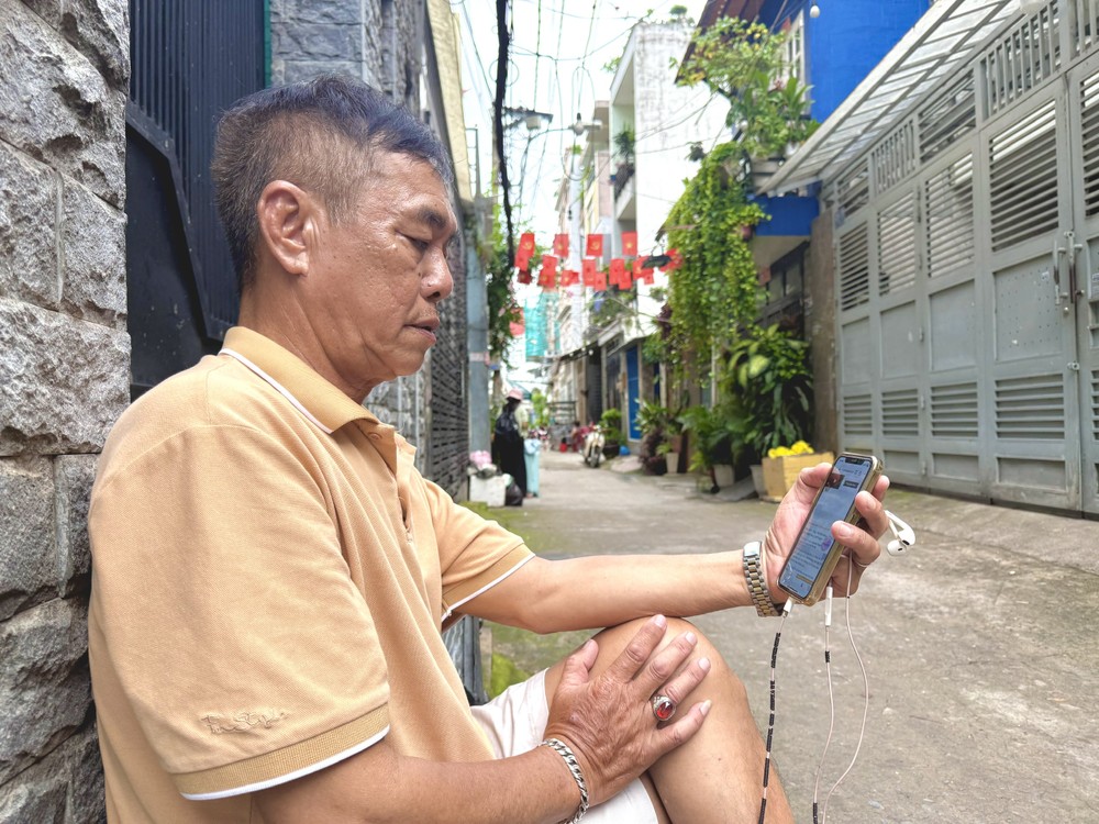Ông Võ Đình Ngãi đọc thông tin về món quà tặng 100.000 đồng/người cho toàn dân. Ảnh: HẢI NHI