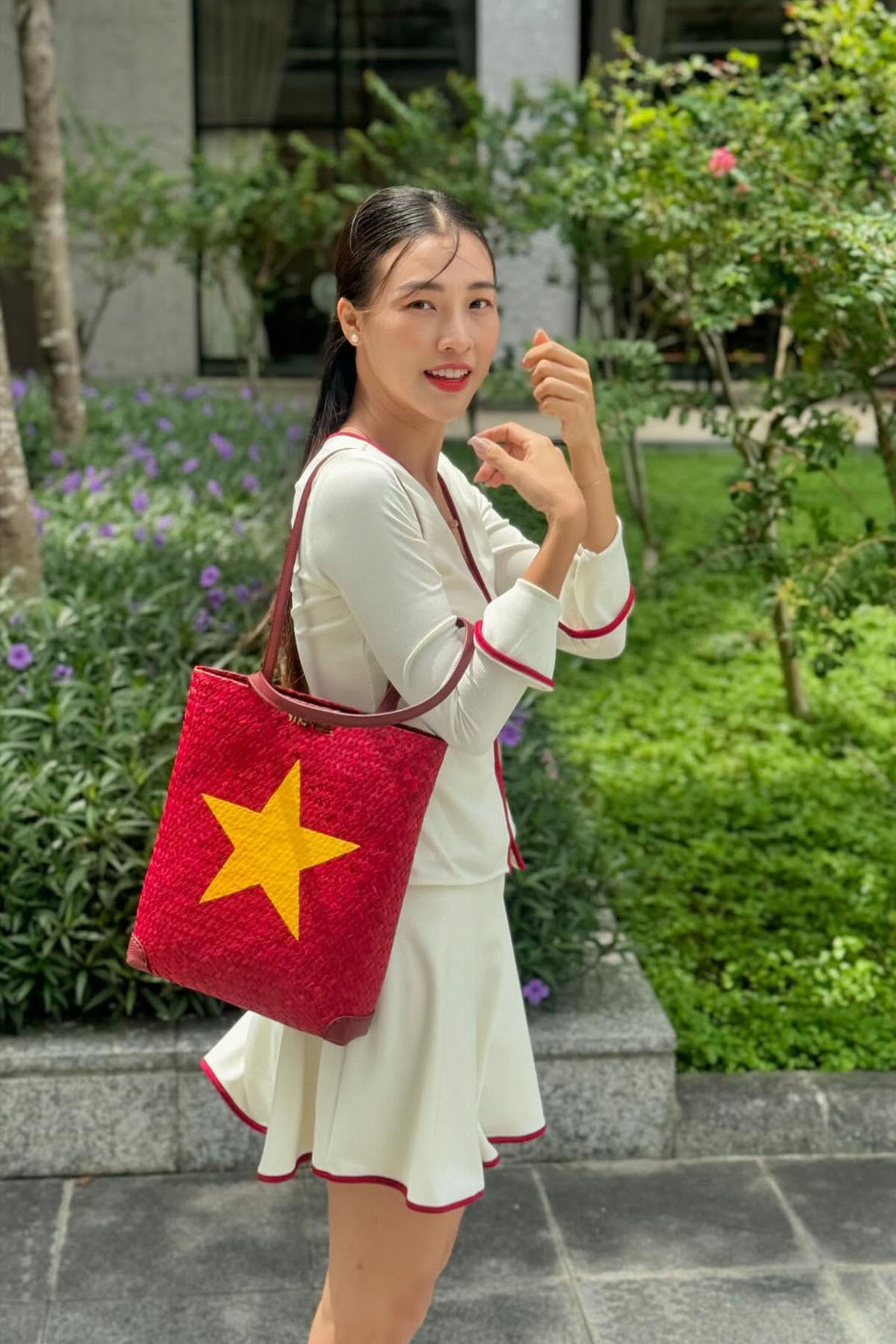 Á hậu Hoàng Oanh xuống phố trong set váy áo nữ tính và đeo túi cói mô phỏng quốc kỳ.
