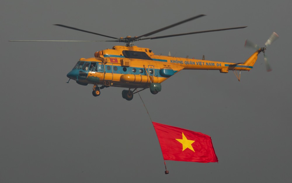 Dẫn đầu là biên đội trực thăng Mi-171, Mi-17, Mi-8, mang cờ Đảng, cờ Tổ quốc tung bay trên Quảng trường Ba Đình lịch sử. Biểu tượng cho sức mạnh đại đoàn kết, niềm tự hào của Đảng và dân tộc, thể hiện bản lĩnh, trí tuệ, khát vọng xây dựng đất nước cất cánh, vươn cao trong kỷ nguyên mới. Ảnh: QUANG ANH - PHI HÙNG