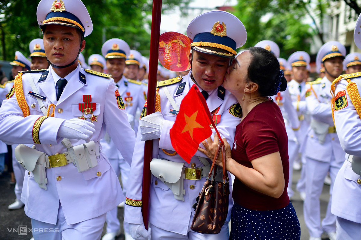 Ba Trần Thị Nhung chờ đón con trai, chiến sĩ Trần Đình Đức, trong tổ quân kỳ khối Nam sĩ quan Hải quân cùng đồng đội đi về trên phố. Tôi hạnh phúc khi được thấy con mình cống hiến cho Tổ quốc, bà nói. Ảnh: Thanh Tùng