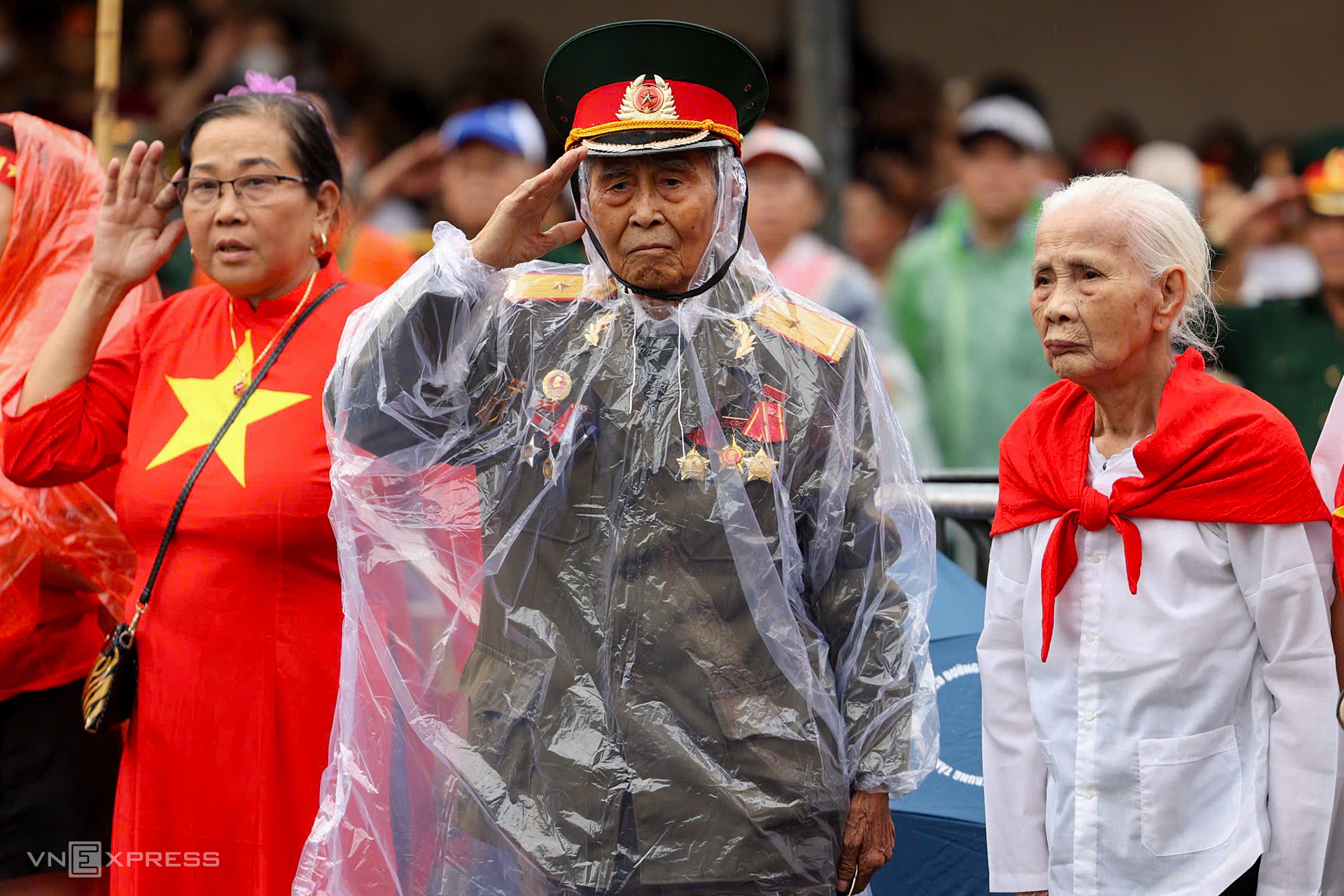Một cựu chiến binh đội áo mưa, giơ tay chào đoàn diễu binh trên phố Tràng Tiền. Những ngày qua, đông đảo cựu chiến binh trên khắp cả nước lặn lội về Thủ đô, bất chấp nắng mưa để dự lễ kỷ niệm Quốc khánh. Ảnh: Quỳnh Trần