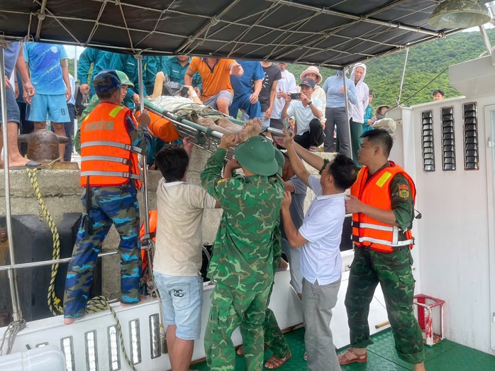Người dân và lực lượng biên phòng đưa bệnh nhân lên xuồng để đi cấp cứu
