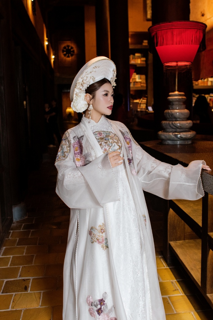 Quán quân Sao Mai dòng nhạc dân gian 2015 Nguyễn Thu Hằng lộng lẫy trong bộ áo dài trắng kết hợp với mấn đội, lấy cảm hứng từ những giá trị đặc sắc của văn hóa truyền thống Việt Nam do NTK Cao Minh Tiến thực hiện.