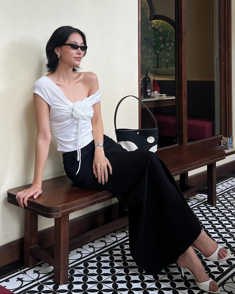 Sự kết hợp trắng – đen kinh điển trở nên thời thượng nhờ áo lệch vai nhấn hoa nổi bật. 