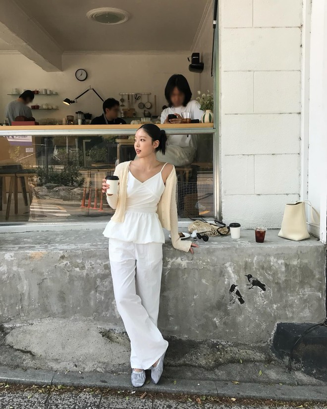 Set đồ trắng toàn tập với áo hai dây peplum kết hợp quần suông mang đến vẻ năng động mà không kém phần nữ tính. Chiếc cardigan mỏng màu kem trở thành lớp phủ nhẹ, tạo chiều sâu trang phục mà vẫn giữ nguyên tinh thần tối giản.