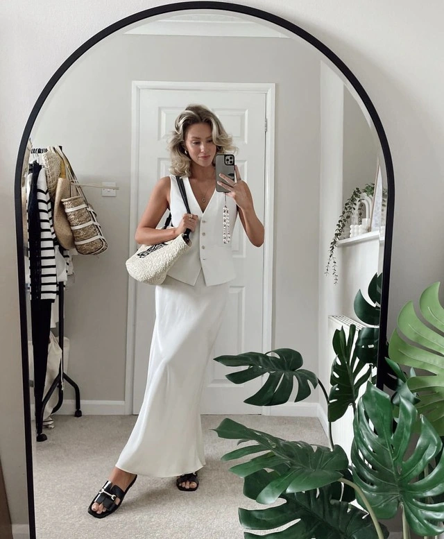 Blogger thời trang Liv Blackwell ứng dụng thành công phong cách white on white thông qua bản phối mix áo gile cùng chân váy satin trắng.