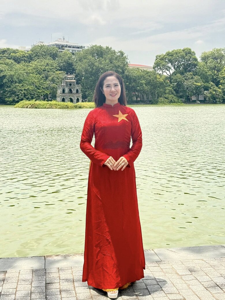 NSƯT Nguyệt hằng mặc áo dài đỏ truyền thống với chi tiết ngôi sao vàng lớn ở ngực áo khẳng định tinh thần dân tộc rõ nét. Không phụ kiện cầu kỳ, chỉ với mái tóc buông tự nhiên và nụ cười hiền hòa, phong cách này toát lên sự mộc mạc nhưng đầy trang trọng.