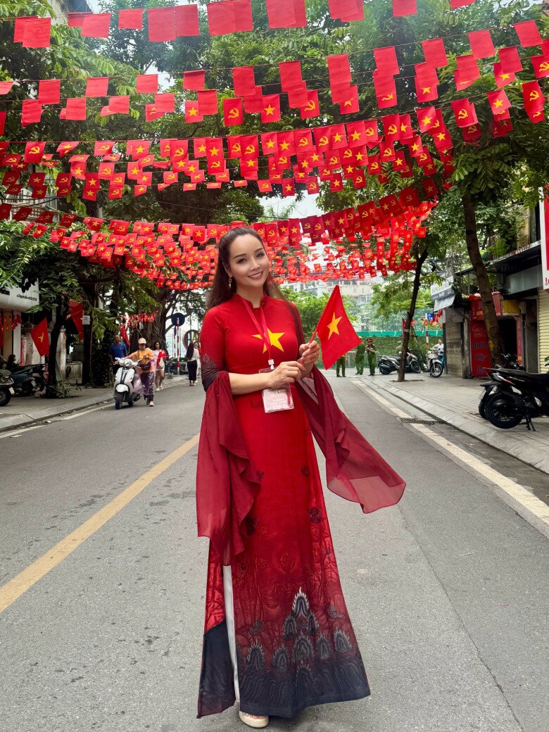 Trong không gian rợp cờ đỏ, tà áo dài đỏ loang đen của Mai Thu Huyền tạo hiệu ứng thị giác độc đáo, vừa cổ điển vừa mới mẻ. Chi tiết tay voan buông rủ làm tăng thêm sự duyên dáng, mềm mại. 