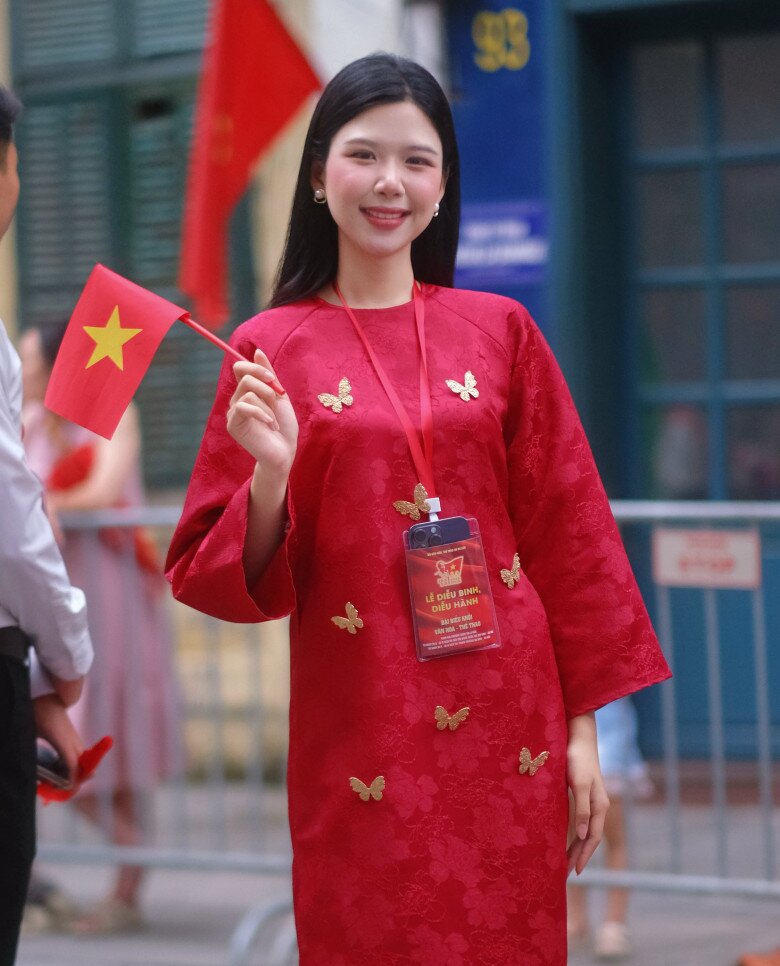 Tham gia hợp luyện diễu binh, Đại sứ Thời trang và Thể thao Đinh Hoàng Linh Đan mặc áo dài đỏ có thêu hình bướm và hoa tiết hoa chìm trông trẻ trung, tươi tắn. 