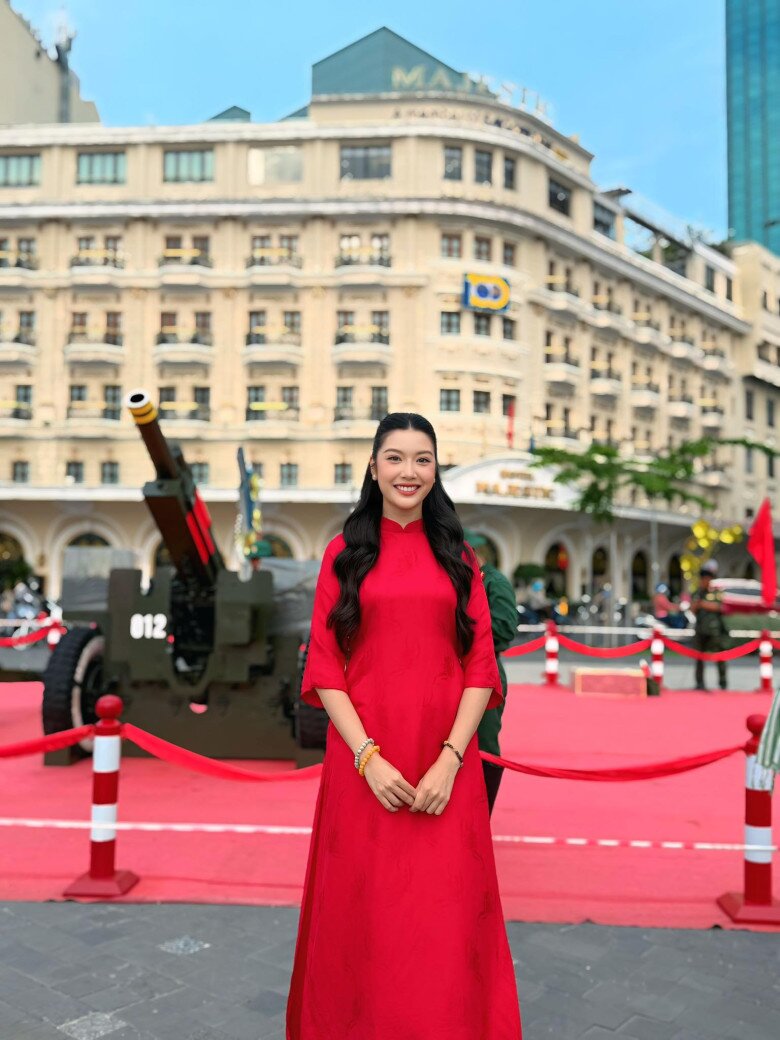 Á hậu Thúy Vân khoe vẻ đẹp nền nà trong tà áo dài đỏ trơn, phom suông cổ điển. Kiểu tóc uốn xoăn sóng dài buông nhẹ, tôn nét dịu dàng. Phụ kiện tối giản với vòng tay gỗ, tạo cảm giác thanh lịch, tinh tế.