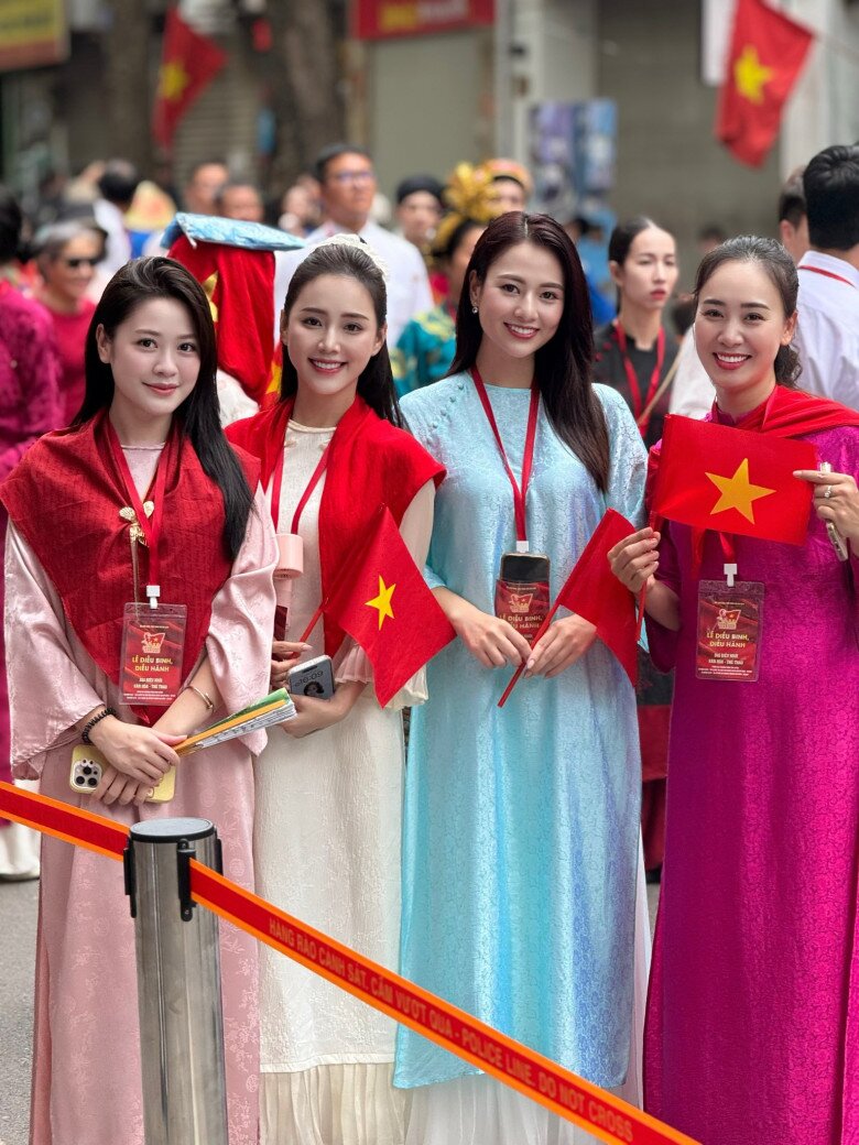 Dàn mỹ nhân VTV khoe sắc trong tà áo dài đủ gam màu: hồng phấn, trắng, xanh ngọc, tím cánh sen. Thiết kế suông rộng tối giản, điểm nhấn là khăn choàng đỏ rực và lá cờ Tổ quốc. Sự đồng điệu tạo nên tổng thể vừa truyền thống vừa trang nhã, nổi bật giữa phố phường rộn ràng.
