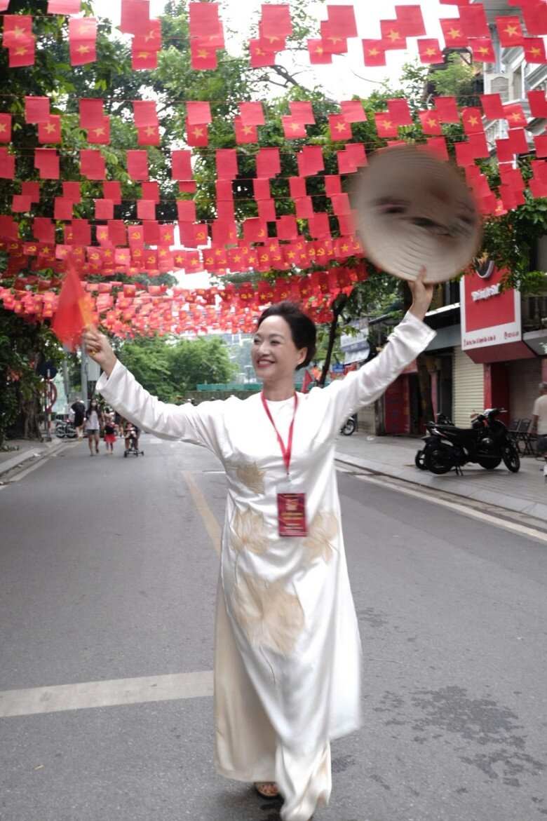 Nữ nghệ sĩ gạo cội Lê Khanh khoác áo dài trắng thêu hoa sen vàng tinh tế, vừa trang nhã vừa thanh khiết. Phụ kiện mộc mạc với nón lá và lá cờ đỏ sao vàng giúp hình ảnh thêm đậm chất truyền thống, đầy tự hào dân tộc.