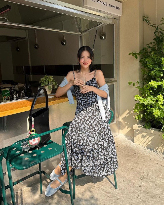 Váy hai dây hoa trắng trên nền đen phối tầng nhún bồng nhẹ. Dáng váy dài giúp kéo dài cơ thể, che vòng hai hiệu quả. Chỉ cần khoác thêm cardigan mỏng là đủ để U40 vừa giấu vai thô, vừa “ăn gian” tuổi mà vẫn thời thượng.