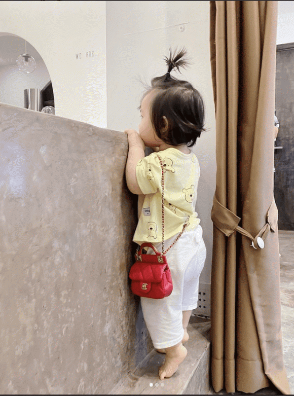 Winnie đứng hóng hớt bố mẹ nhưng trên vai lại mang chiếc túi hiệu đắt tiền.