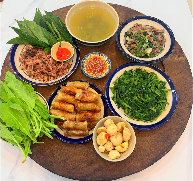 Một mâm cơm phong phú với nhiều món ăn quen thuộc, hấp dẫn: nem rán giòn rụm, cà muối chua giòn, rau muống luộc xanh mát, thêm bò xào đậm đà và nem nướng thơm lừng. Sự kết hợp này tạo nên bữa ăn hài hòa, đủ vị và no bụng.
(Ảnh: Tâm Nguyễn)