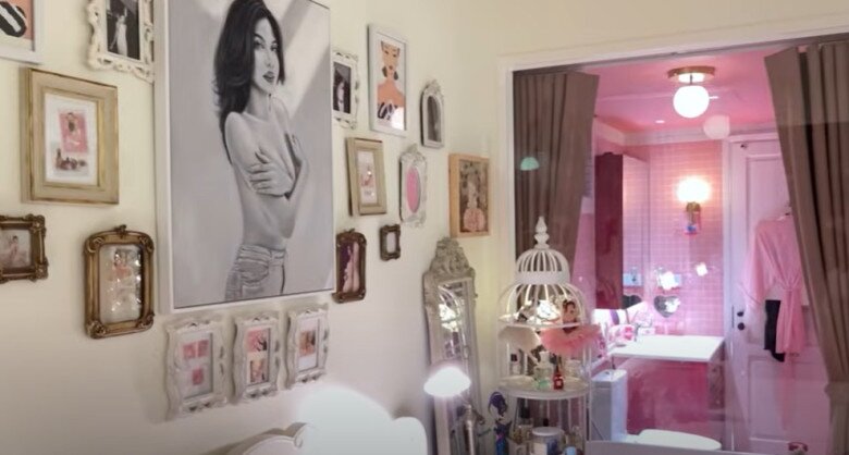 Một mảng tường trong phòng ngủ như một phòng tranh thu nhỏ với ảnh đen trắng, tranh vẽ và ảnh cá nhân. Không gian dẫn ra phòng tắm hồng pastel tạo cảm giác xuyên suốt, lãng mạn.