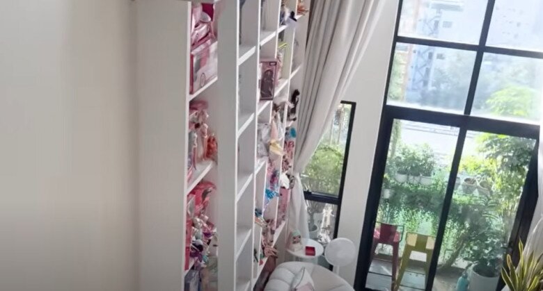 Từ tầng trên nhìn xuống, kệ búp bê cao hơn 6m là điểm nhấn ấn tượng của căn hộ. Ánh sáng tràn vào qua hệ cửa kính lớn, phản chiếu lên những món đồ chơi làm không gian trở nên cổ tích.