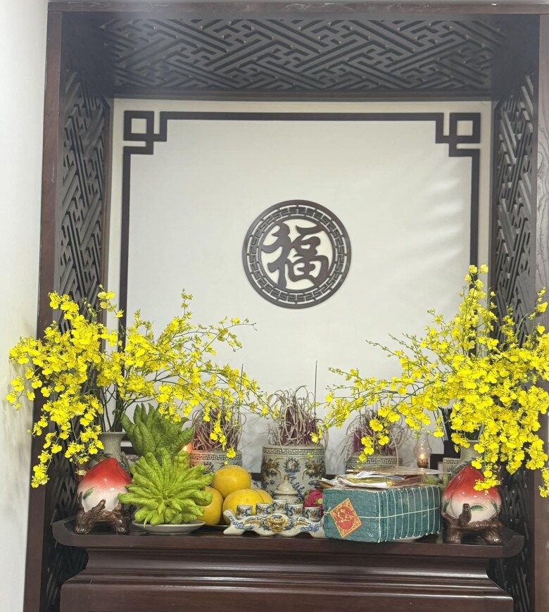 Bàn thờ được đặt ở vị trí trang trọng, gần cửa ban công. Các bình hoa, mâm ngũ quả, vật phẩm thờ cúng được sắp xếp gọn gàng. Họa tiết chạm khắc gỗ giúp tăng tính truyền thống.