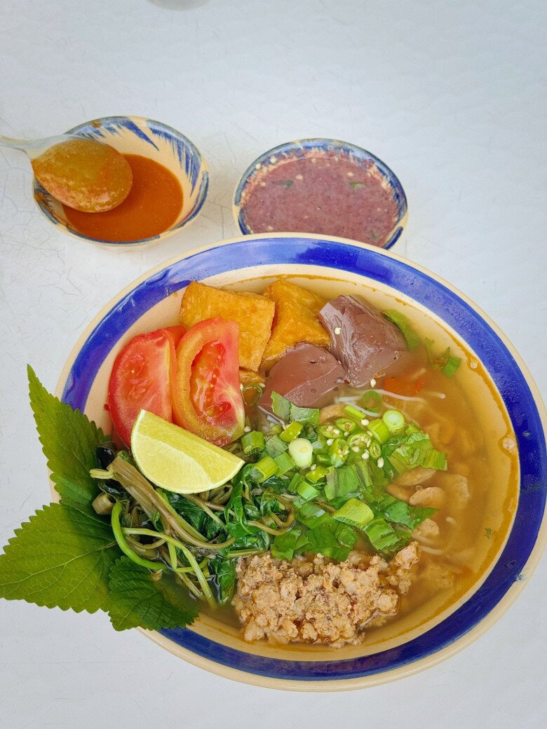 Bún riêu thanh đạm chồng nấu làm người đẹp xuýt xoa: “Húp thêm một muỗng nước lèo thanh ngọt được nấu từ tôm khô và khô mực, cũng không thể thiếu miếng riêu cua thịt nấu vừa vị và một cục đậu chiên chấm mắm ruốc pha”.