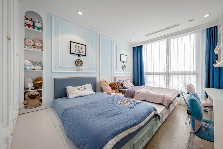 Phòng ngủ dành cho các con của nam nhạc sĩ với hai giường pastel và kệ thú bông đáng yêu. Tường xanh nhạt phối trắng, rèm xanh đậm tạo điểm nhấn. Ánh sáng tự nhiên và đồ trang trí mềm mại khiến không gian trở nên nhẹ nhàng, ngọt ngào.