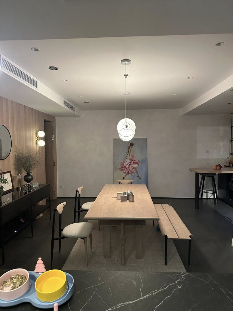 Khu vực bàn ăn đơn giản nhưng tinh tế với bàn gỗ dài, ghế phối vải màu trung tính. Trên tường treo tranh lớn vẽ cô gái trong váy hồng, điểm nhấn nghệ thuật khiến góc ăn uống vừa gần gũi vừa sang trọng.