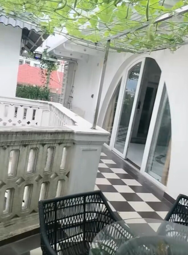 Sân thượng lát gạch caro trắng đen, kết hợp cùng bộ bàn ghế mây đen tạo nên không gian thư giãn ngoài trời lý tưởng. Từ đây, có thể ngắm trọn giàn rau xanh mướt vắt ngang qua hiên nhà.