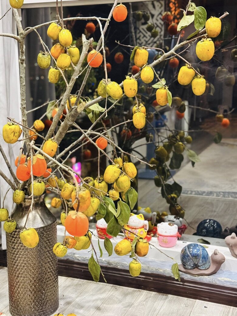 Không chỉ gia đình Tự Long, nữ BTV VTV Hoàng Trang cũng thích trưng cành hồng trong phòng khách. Bình hồng quả lớn đặt gần cửa kính, phía dưới là những chú mèo thần tài và ốc sứ trang trí.