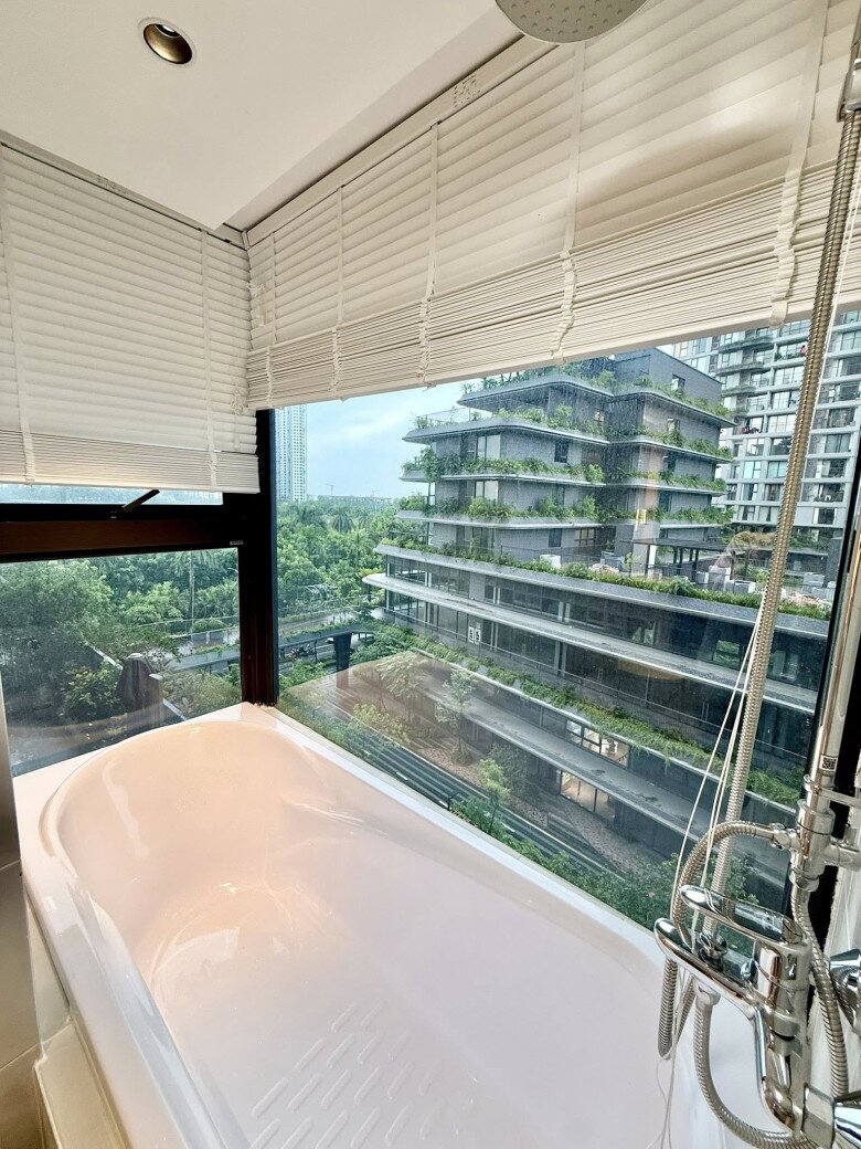 Chiếc bồn tắm đặt ngay bên khung kính lớn với góc nhìn thẳng ra tòa nhà có rất nhiều cây xanh. Khung cảnh một ngày mưa càng làm nổi bật sự bình yên và riêng tư của góc thư giãn này.