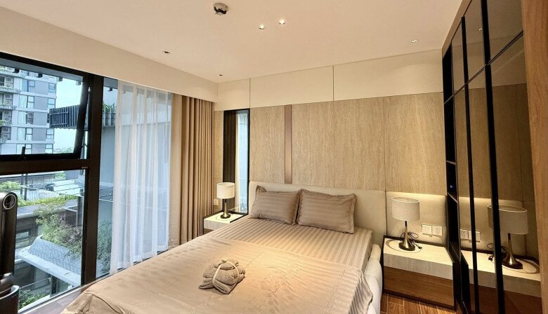Phòng ngủ master với tông màu beige và nâu nhạt chủ đạo, kết hợp cùng ánh đèn vàng dịu mắt tạo cảm giác thư giãn tuyệt đối. Tủ quần áo cánh kính, bàn đầu giường đồng bộ, mọi chi tiết đều chỉn chu và hài hòa.