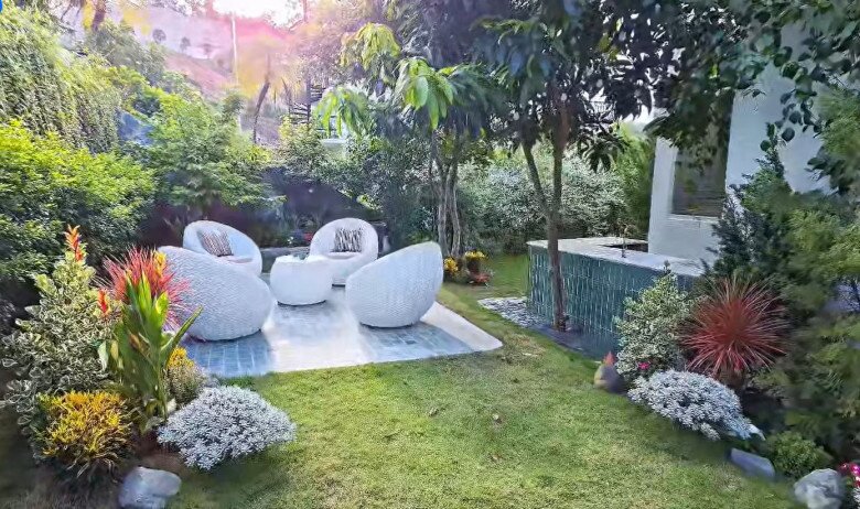 Không gian tiếp khách ngoài trời nổi bật với bộ ghế hình khối tròn độc đáo, lát nền gạch xanh lam hài hòa với thiên nhiên.