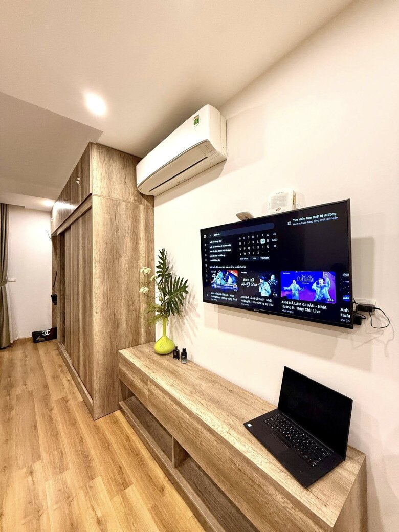 Kệ tivi gỗ đồng bộ với toàn bộ nội thất, bên trên là tivi treo tường tiện nghi và gọn gàng. Góc nhỏ lọ hoa, tinh dầu tạo cảm giác hiện đại nhưng không kém phần mềm mại.