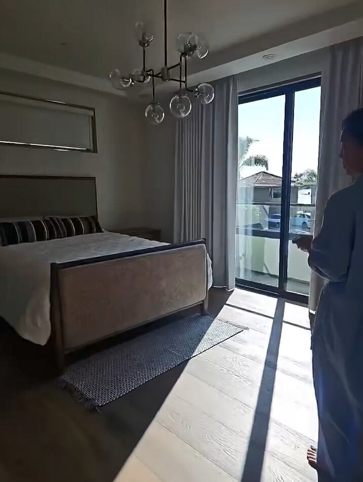  Phòng ngủ chính trên lầu với sàn gỗ, cửa kính lớn đón nắng sáng. Tone màu trắng - kem nhẹ nhàng, kết hợp ánh sáng tự nhiên khiến căn phòng luôn thoáng đãng và yên tĩnh.