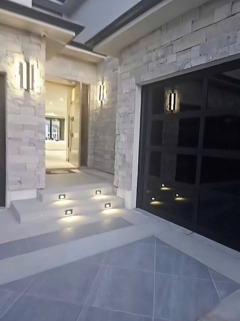  Lối vào nhà lát đá sạch sẽ, với các bậc tam cấp gắn đèn LED âm sàn. Chi tiết nhỏ nhưng tạo cảm giác chào đón và ấm cúng, nhất là khi trời tối.