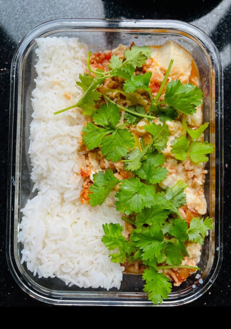 Cơm trắng ăn kèm đậu hũ sốt cà chua thịt bằm, phủ ngập rau mùi xanh mướt. Món ăn đơn giản nhưng đậm đà, hương vị cơm nhà cho ngày học tập bận rộn.