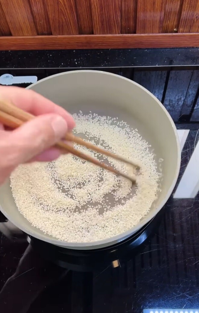 Theo yêu cầu của con gái, anh làm món cá hồi ngâm tương cho 5 người ăn. Đầu tiên là bước rang mè trắng cho vừa chín tới, không để cháy.