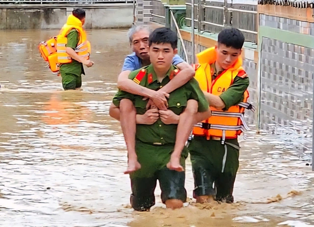 Lực lượng công an hỗ trợ người dân vùng lũ đến nơi an toàn.