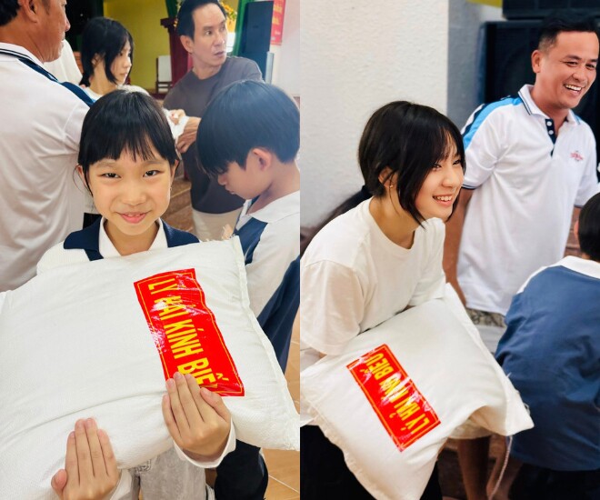 2 con gái của cặp đôi khệ nệ bê bao gạo 10kg để tặng bà con.