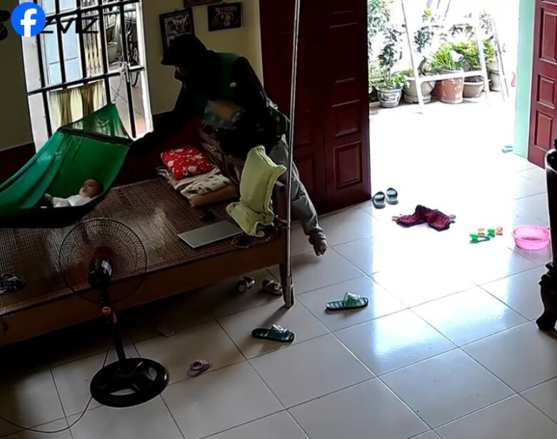 Anh đung đưa nhẹ võng để dỗ dành em bé.