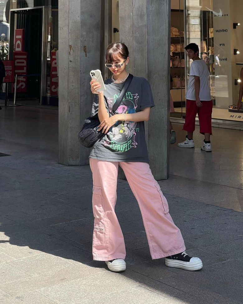 Đây là Min đúng chuẩn trendy girl với áo phông graphic oversized, quần cargo hồng pastel và giày sneaker đế bánh mì. Kính mắt mèo trắng và túi chéo vải càng tăng thêm chất thời trang đường phố. Tổng thể toát lên cảm giác thoải mái nhưng cực kỳ có gu - kiểu phối đồ mà Gen Z nào cũng muốn học theo.