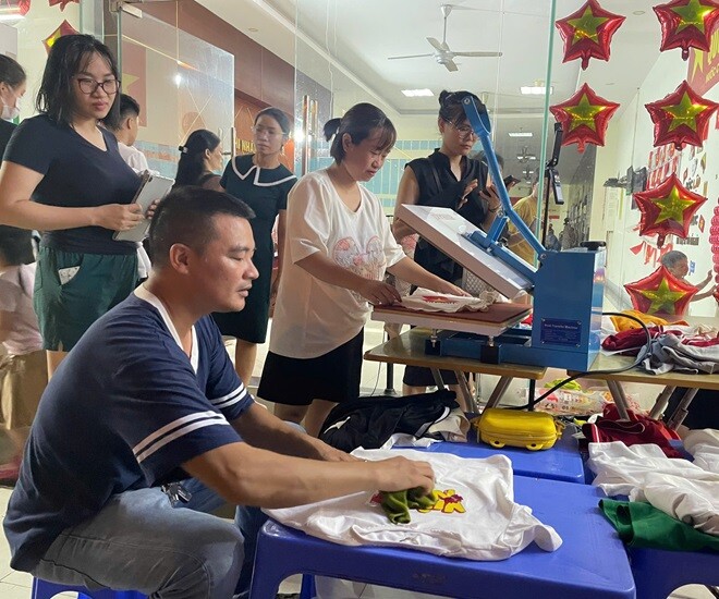 Với chiếc máy in sẵn có, chị Chi và anh Tiến cùng các thành viên sẵn sàng in miễn phí áo cho người dân. 